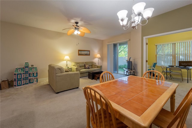 carpeted dining space with ceiling fan with notable chandelier