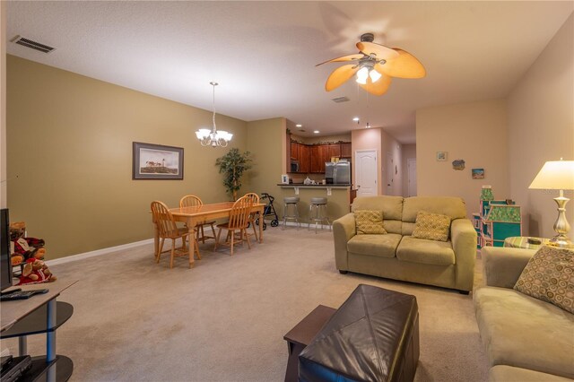 living room with ceiling fan with notable chandelier and light colored carpet