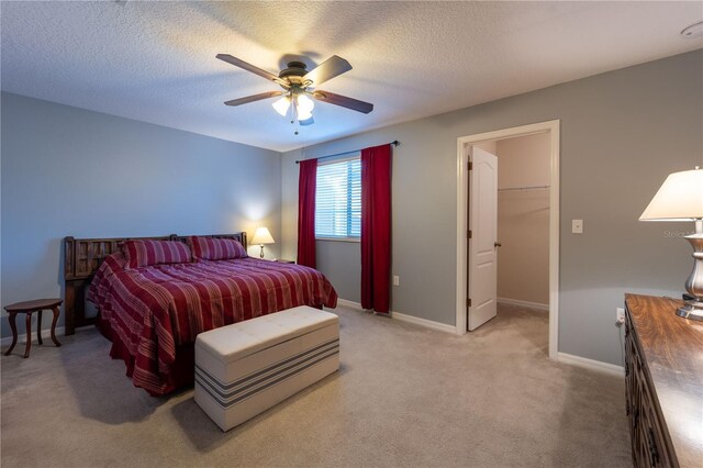 carpeted bedroom featuring ceiling fan, a closet, a textured ceiling, and a walk in closet