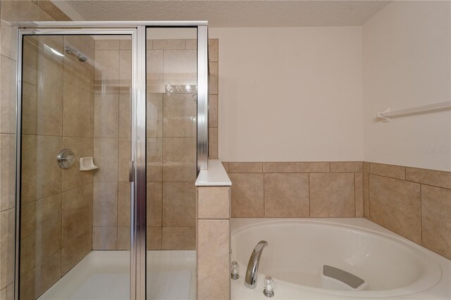 bathroom featuring plus walk in shower and a textured ceiling