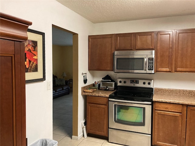 kitchen featuring appliances with stainless steel finishes, a textured ceiling, and light tile patterned floors