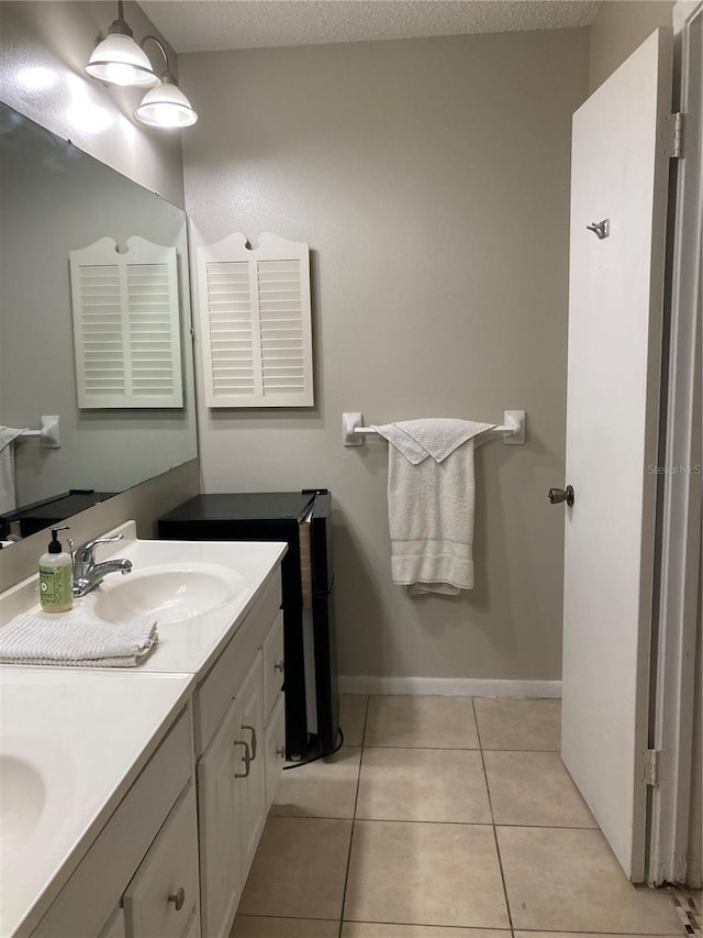 bathroom featuring a textured ceiling, double sink vanity, and tile patterned floors