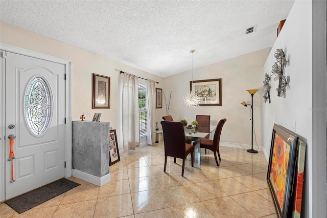 dining room with a textured ceiling, vaulted ceiling, and light tile patterned floors