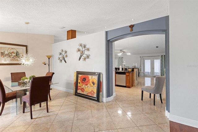 tiled dining area with ceiling fan, french doors, and a textured ceiling