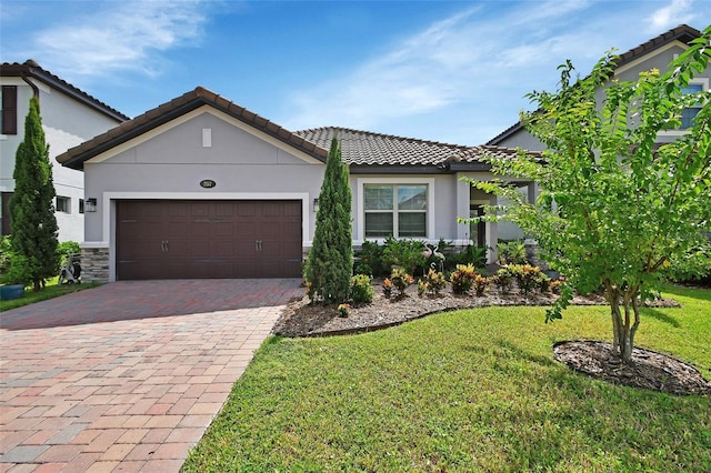 view of front of property featuring an attached garage, a tiled roof, decorative driveway, stucco siding, and a front yard