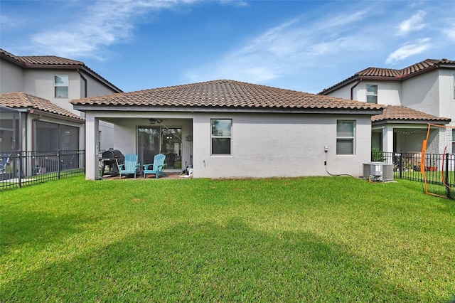 rear view of property with ceiling fan, a yard, and central AC unit