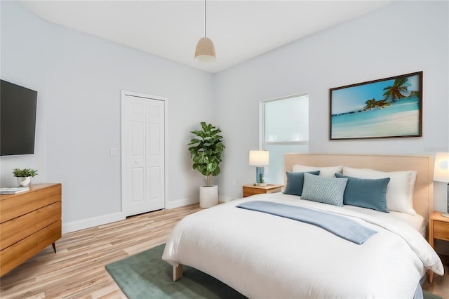 bedroom with light wood-style flooring, baseboards, and a closet