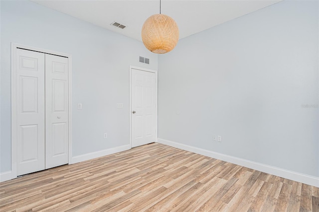 unfurnished bedroom featuring baseboards, visible vents, and light wood finished floors