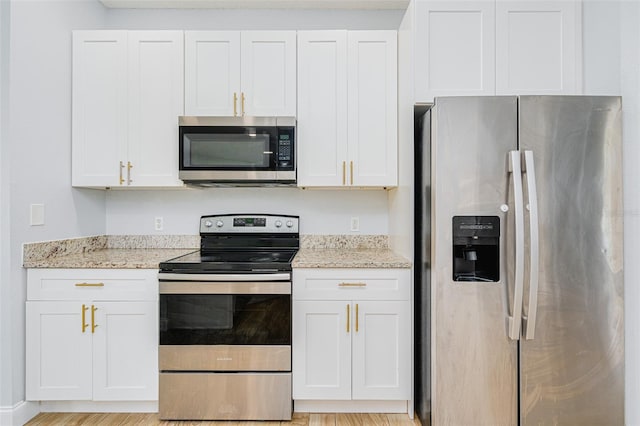 kitchen featuring white cabinets, light stone countertops, light wood-style flooring, and stainless steel appliances