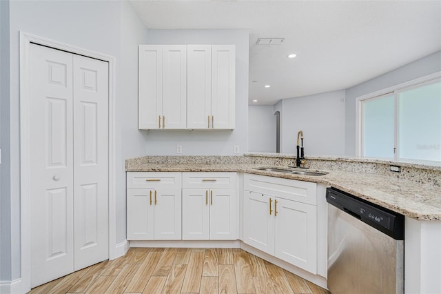 kitchen featuring light wood finished floors, dishwasher, light stone countertops, white cabinetry, and a sink