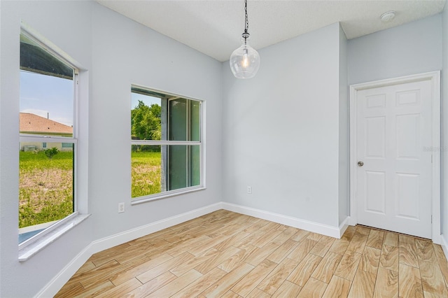 spare room featuring light wood-style floors and baseboards