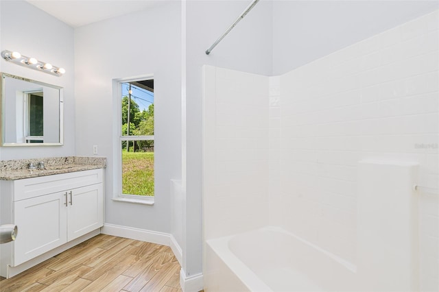 bathroom with  shower combination, baseboards, wood finished floors, and vanity