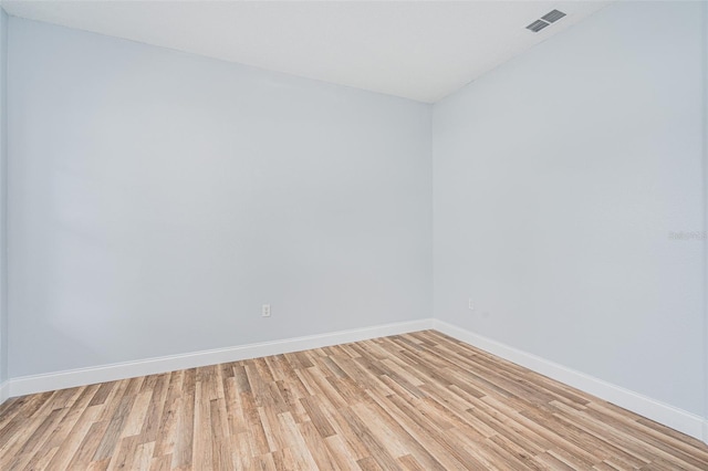 spare room with light wood-style flooring, visible vents, and baseboards