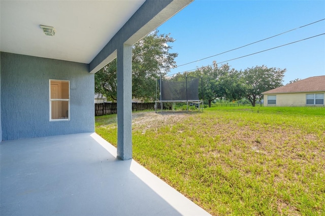 view of yard with a trampoline, a patio area, and fence