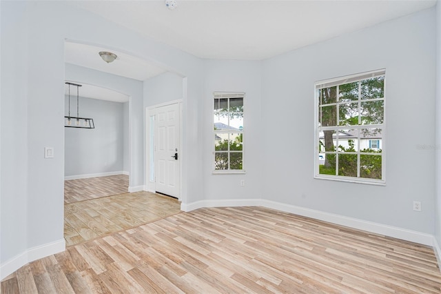 unfurnished room featuring light wood-type flooring, a healthy amount of sunlight, and baseboards