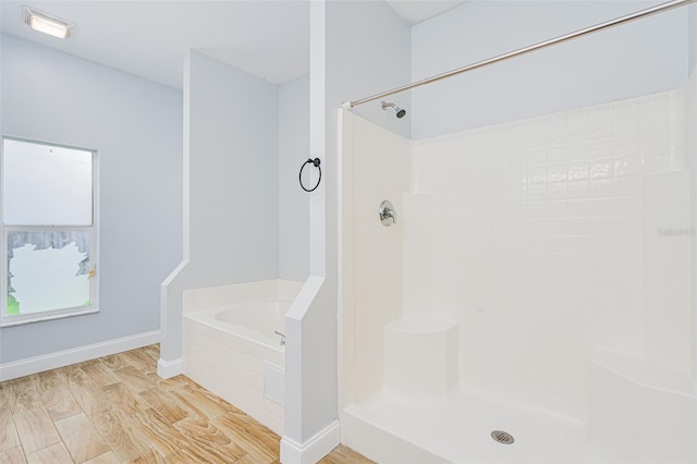 bathroom with a shower, baseboards, a bath, and wood finished floors