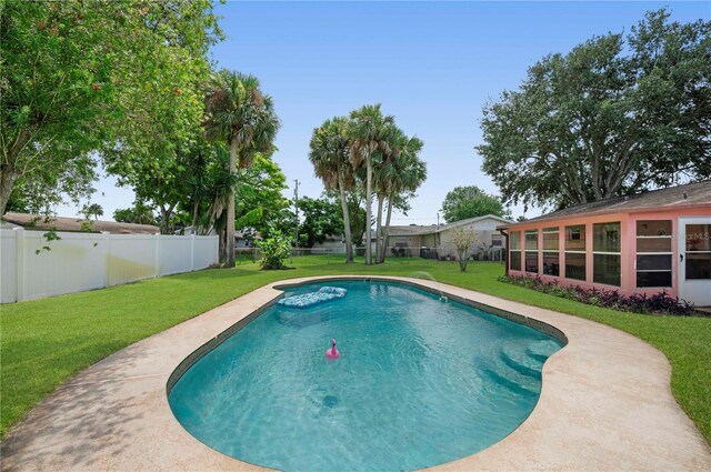 view of swimming pool featuring a sunroom and a lawn