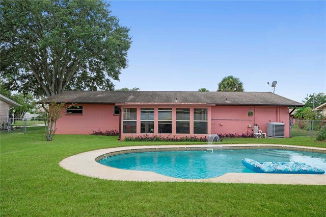 view of swimming pool featuring central air condition unit, pool water feature, and a lawn