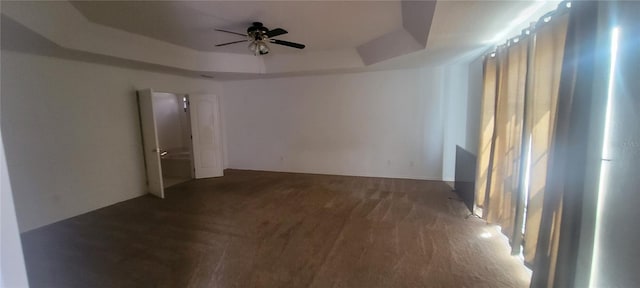 empty room featuring ceiling fan and a raised ceiling