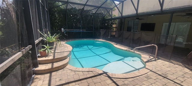 view of pool with glass enclosure, a patio, and ceiling fan