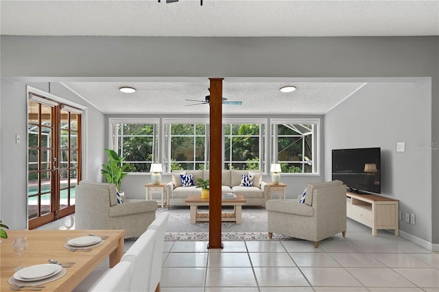 living room with a textured ceiling, light tile patterned floors, ceiling fan, and french doors