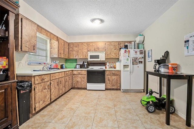 kitchen with a textured ceiling, white appliances, light tile patterned floors, and sink