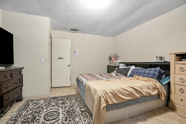 tiled bedroom featuring a textured ceiling