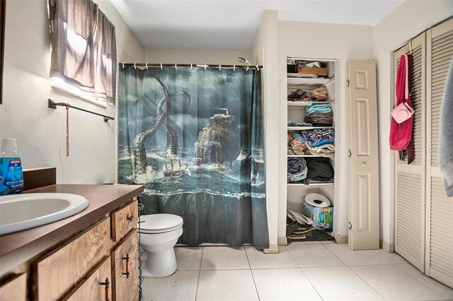 bathroom with tile patterned floors, toilet, vanity, and curtained shower