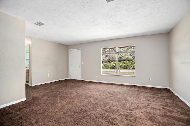 unfurnished room featuring a textured ceiling and dark colored carpet