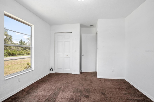 unfurnished bedroom featuring a closet and dark colored carpet