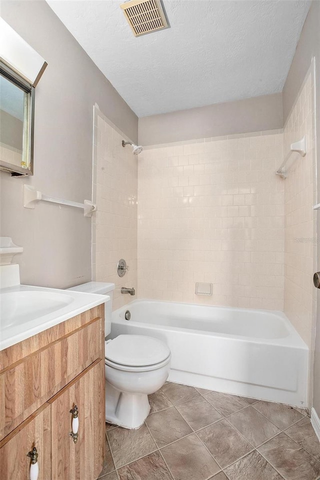 full bathroom featuring toilet, tile patterned flooring, vanity, a textured ceiling, and tiled shower / bath combo