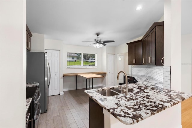 kitchen with light hardwood / wood-style flooring, kitchen peninsula, stainless steel range with electric cooktop, and sink