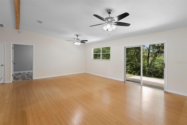 unfurnished room featuring light wood-type flooring, beam ceiling, and a healthy amount of sunlight