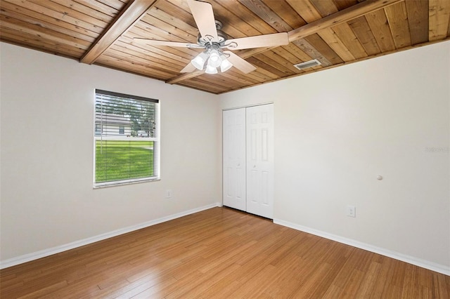 unfurnished bedroom with ceiling fan, hardwood / wood-style floors, beam ceiling, a closet, and wood ceiling