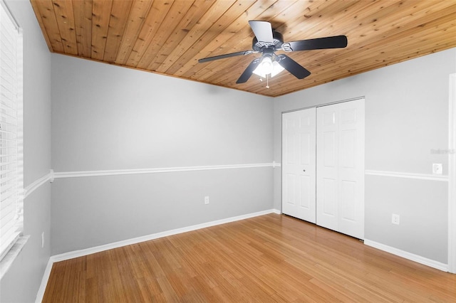 unfurnished bedroom featuring ceiling fan, a closet, hardwood / wood-style floors, and wood ceiling