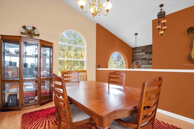 dining space with high vaulted ceiling, a chandelier, and hardwood / wood-style floors