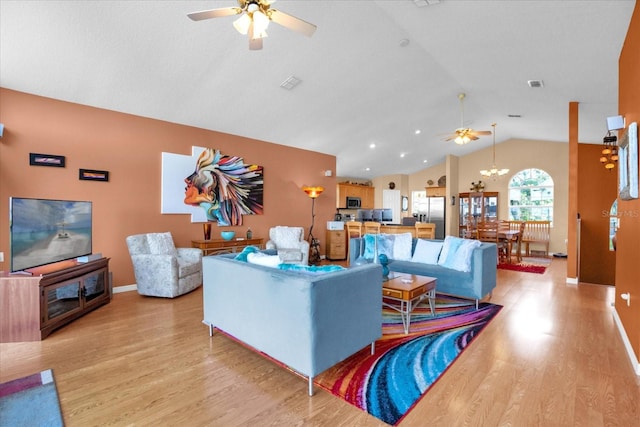 living room with ceiling fan with notable chandelier, lofted ceiling, and light hardwood / wood-style floors