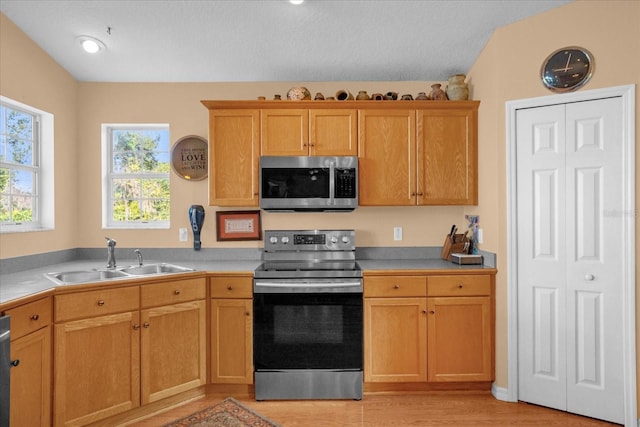 kitchen featuring lofted ceiling, sink, a textured ceiling, appliances with stainless steel finishes, and light hardwood / wood-style floors