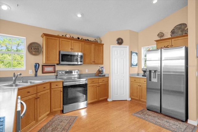 kitchen featuring stainless steel appliances, lofted ceiling, light wood-type flooring, and sink