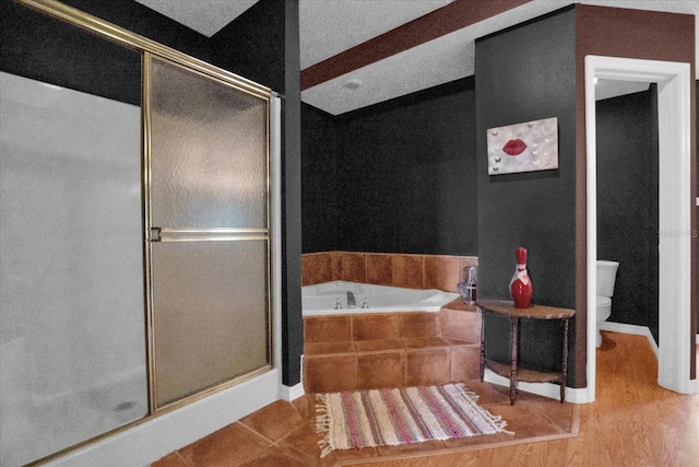 bathroom featuring toilet, plus walk in shower, and hardwood / wood-style flooring