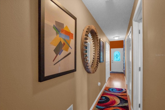 hall with a textured ceiling and hardwood / wood-style floors