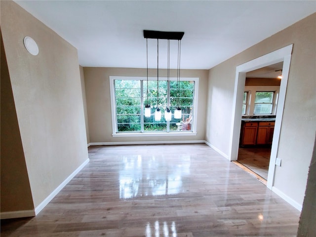 unfurnished dining area featuring light wood-type flooring and a notable chandelier