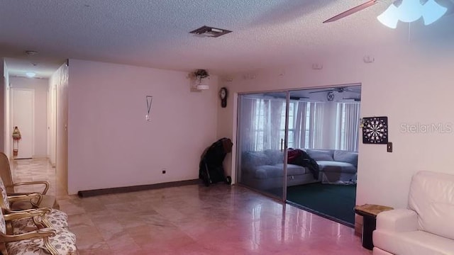 living room with ceiling fan and a textured ceiling