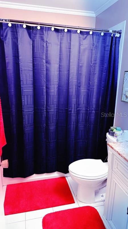 bathroom featuring vanity, a shower with shower curtain, crown molding, toilet, and tile patterned floors