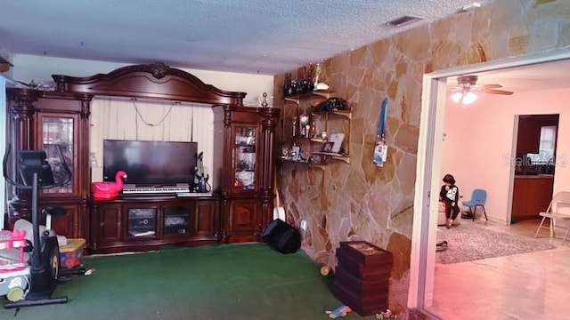 living room featuring tile walls, a textured ceiling, and ceiling fan