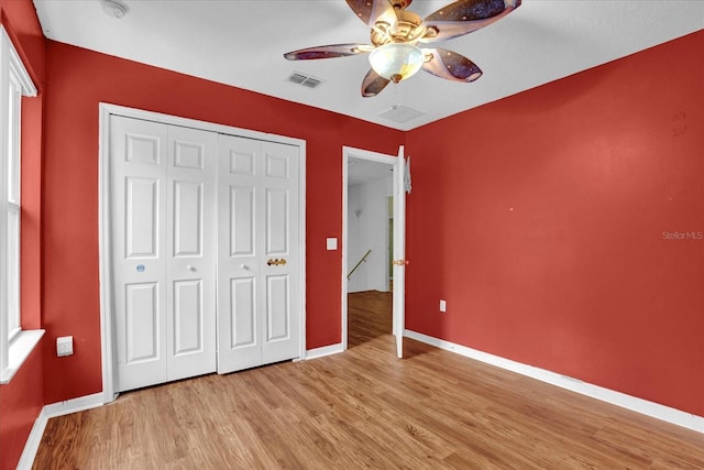 unfurnished bedroom with light hardwood / wood-style floors, a closet, and ceiling fan