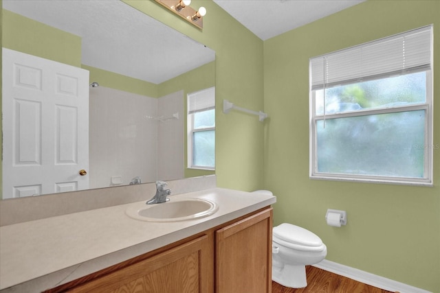 bathroom with hardwood / wood-style floors, a shower, vanity, and toilet