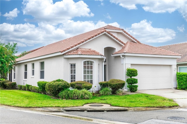 mediterranean / spanish home with a garage and a front lawn