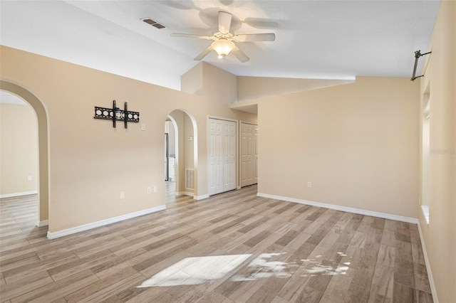 spare room with arched walkways, ceiling fan, visible vents, and light wood-style flooring