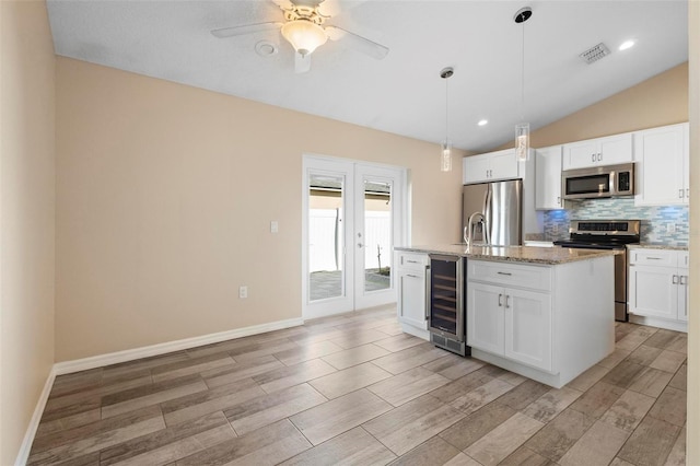 kitchen featuring lofted ceiling, wine cooler, visible vents, appliances with stainless steel finishes, and tasteful backsplash